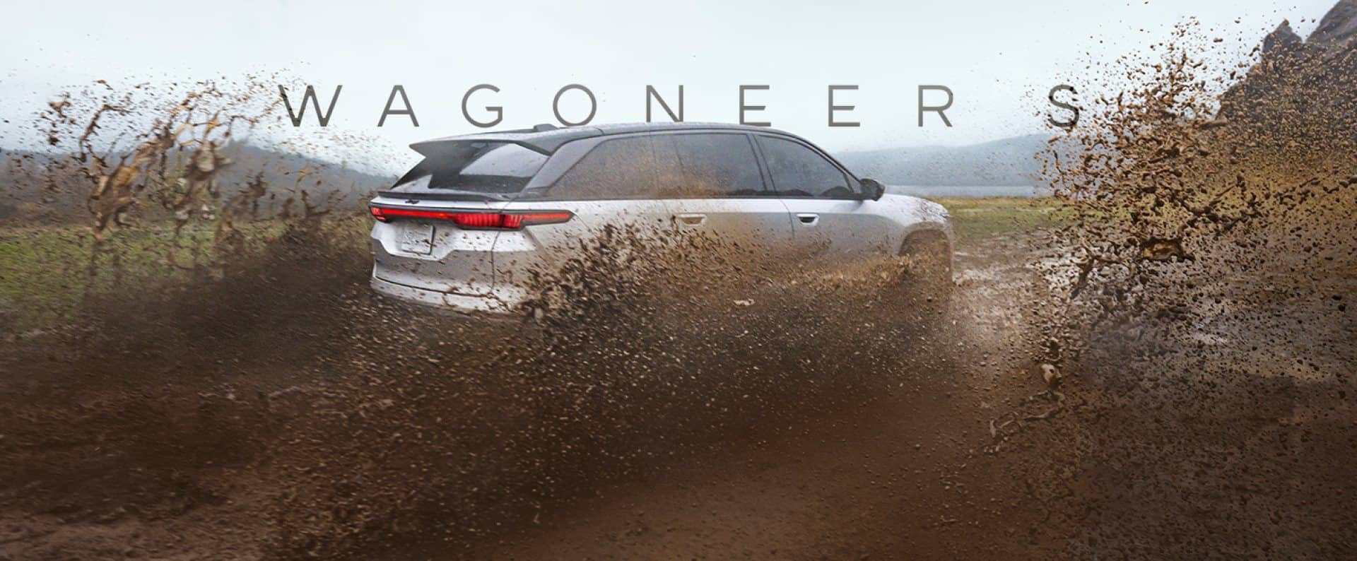 A silver Jeep Wagoneer S Launch Edition kicks up mud as it drives down a dirt road in the country. The words 'WAGONEER S' are superimposed behind it.