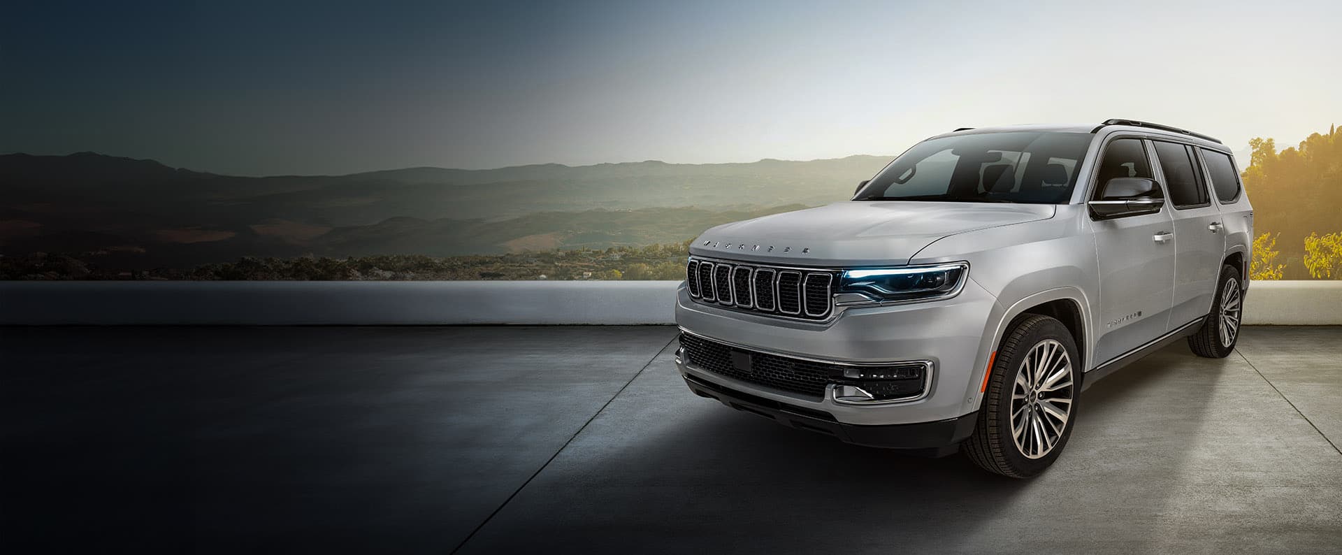 A driver-side front angle of a silver 2025 Jeep Wagoneer Limited with a valley and mountains in the background.