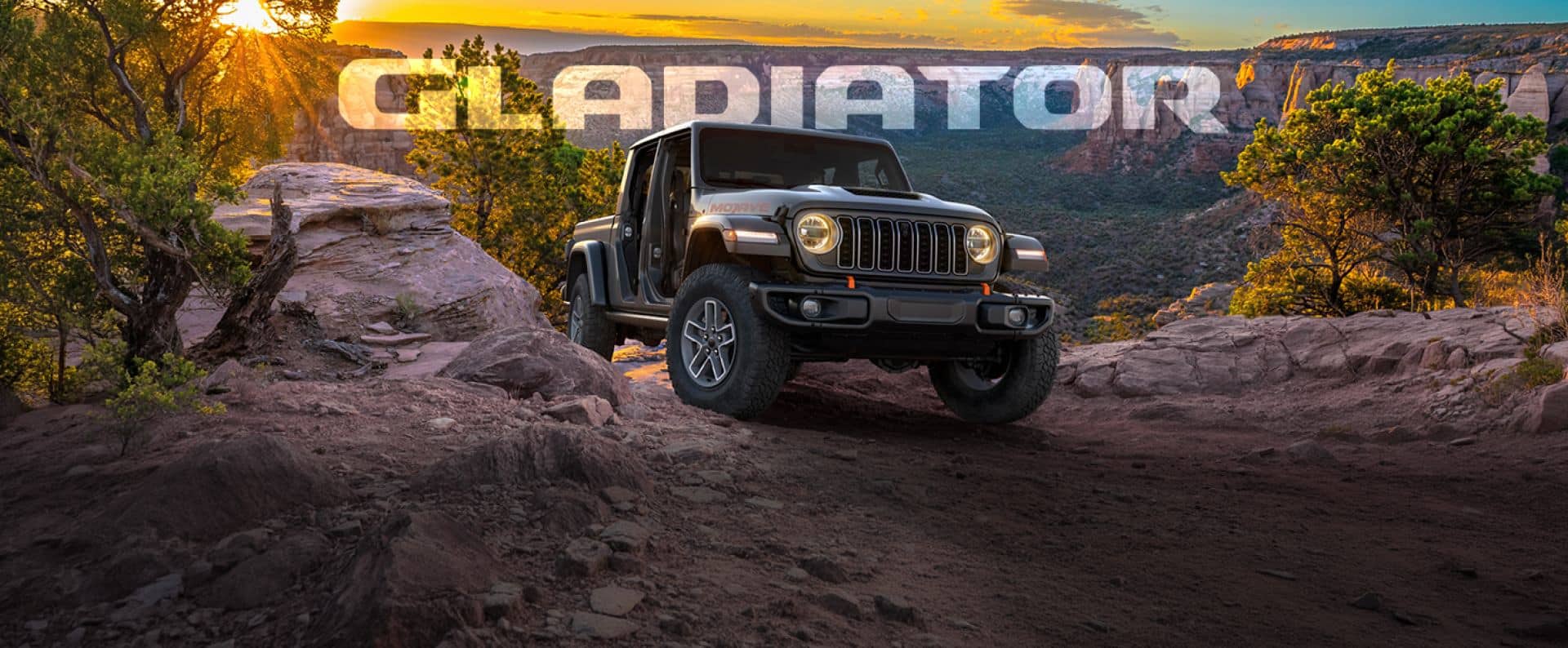 A gray Jeep Gladiator sits at the top of a rocky incline on a wooded mountaintop at sunset. The word 'GLADIATOR' is superimposed behind it.