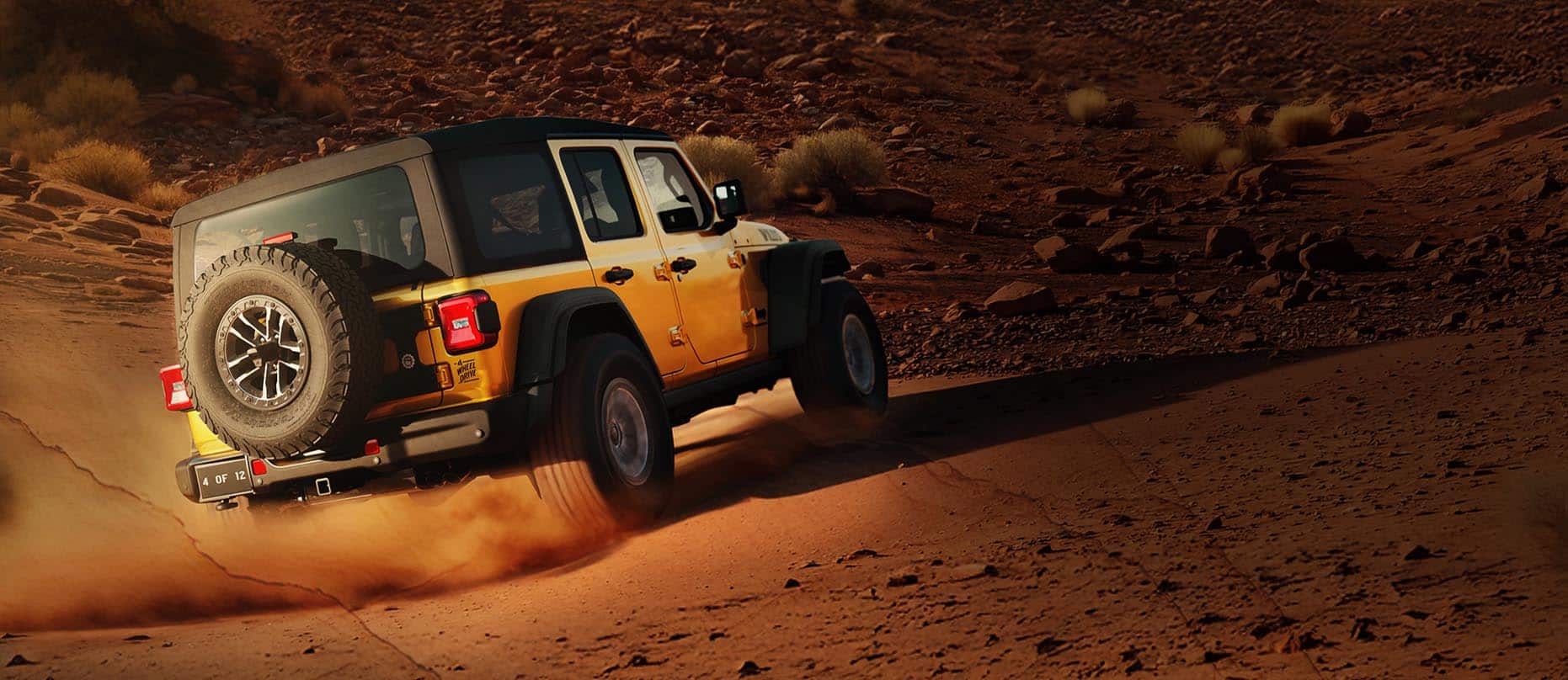 A passenger-side rear angle of a gold 2026 Jeep Wrangler Willys 392 with a black top, traveling on a sandy trail, off-road in the desert.