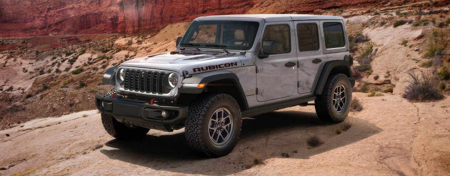 An orange 2023 Jeep Wrangler Rubicon 4xe with the Punk'n limited edition color being driven down a scrubby trail off-road.