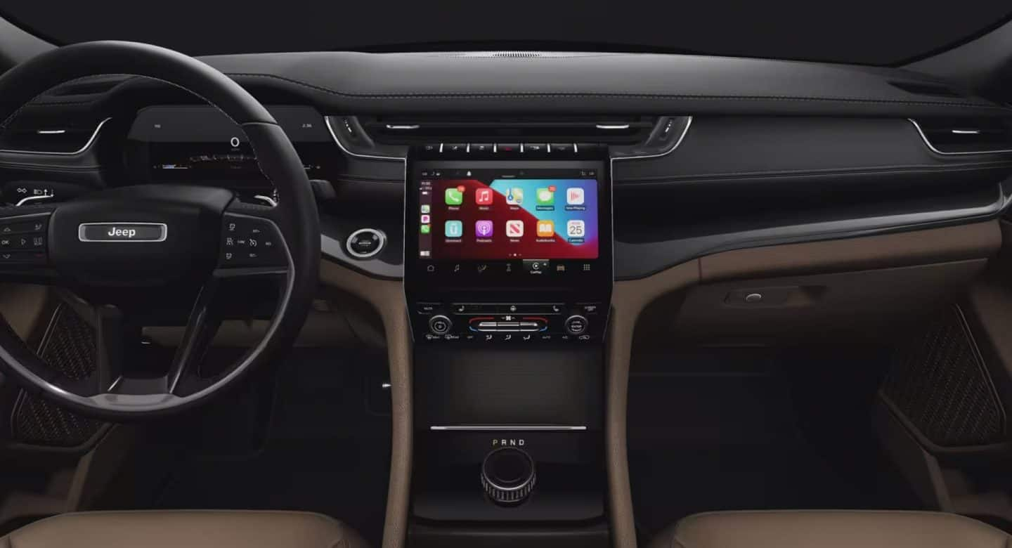 The front row of the 2022 Jeep Grand Cherokee Summit Reserve, in Tupelo Palermo leather, focusing on the steering wheel, touchscreen and dashboard.