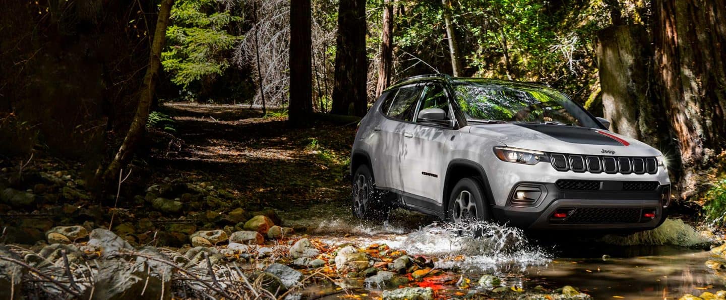 A rear angle of a black 2023 Jeep Grand Cherokee L Altitude as it fords through a stream.