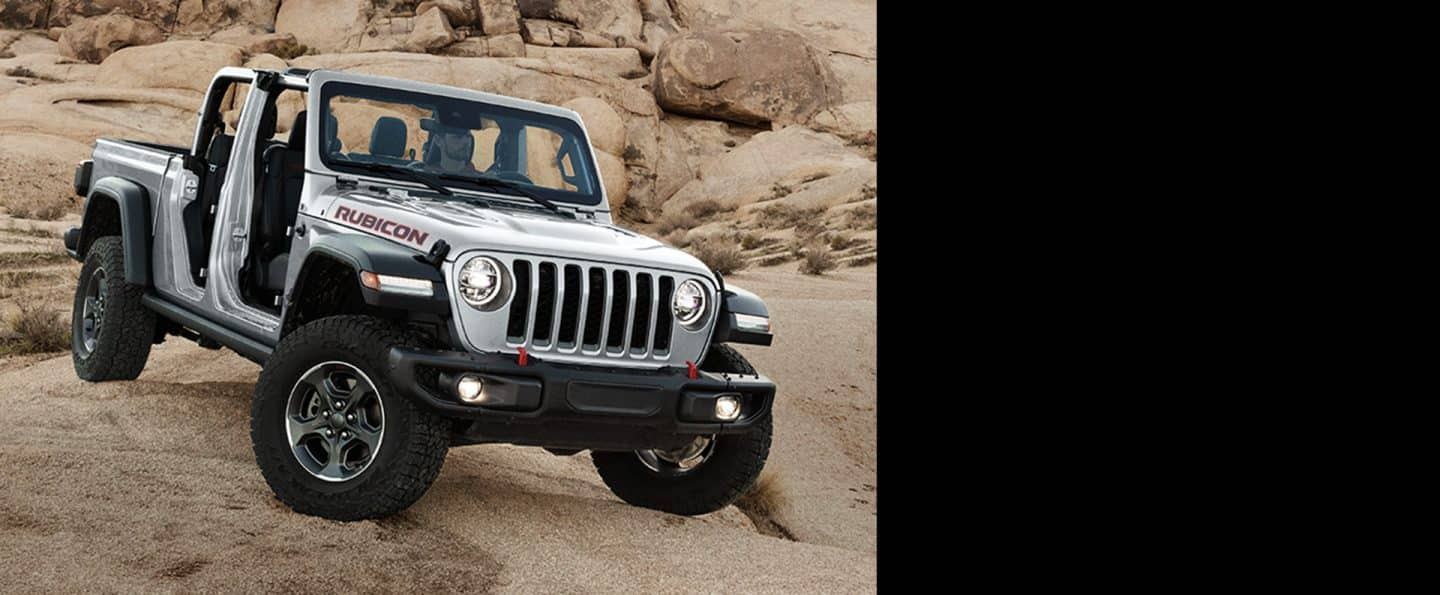 Jeep Gladiator Rubicon 2023 a parcat off-road pe stâncă, cu partea superioară și ușile îndepărtate.