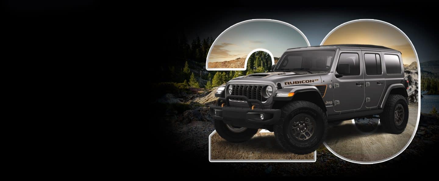 Arxa fonda dağlarla park edilmiş boz 2023 Jeep Wrangler Rubicon 392 20th Anniversary Edition. Böyük yarı şəffaf 20 rəqəmi birbaşa avtomobilin arxasında yerləşir.