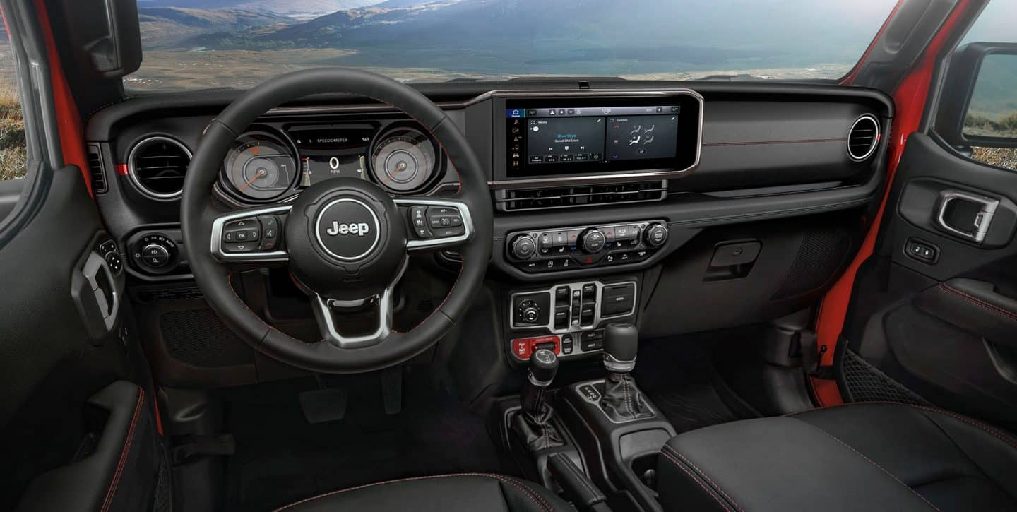 El volante, la pantalla digital de información para el conductor en el panel de instrumentos, la pantalla táctil de Uconnect, los controles de la consola central y el tablero en la Jeep Gladiator Rubicon 2024.