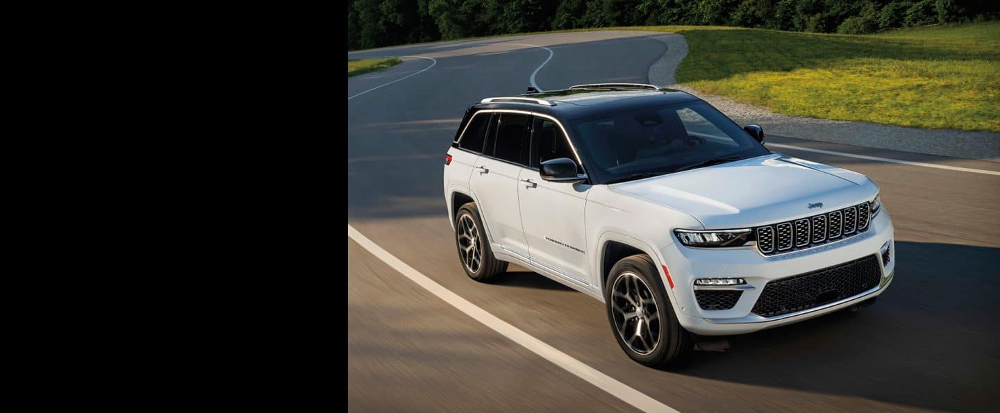 Ağ 2024 Jeep Grand Cherokee Summit Reserve dolanbaclı yolda sürülür.