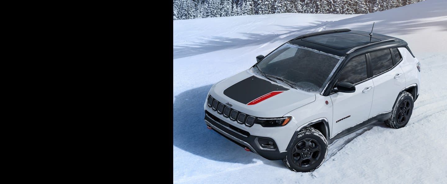 Un Jeep Compass Trailhawk din 2023 condus pe zăpadă, cu o pădure în fundal.