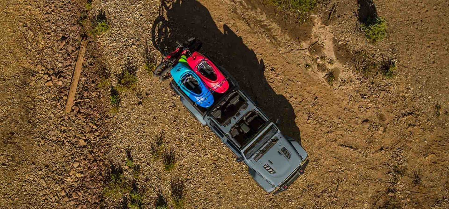 Un ángulo inferior de una Jeep Gladiator Mojave X 2025 gris sin las puertas ni el techo circulando por la arena floja, dejando huellas pesadas a su paso.