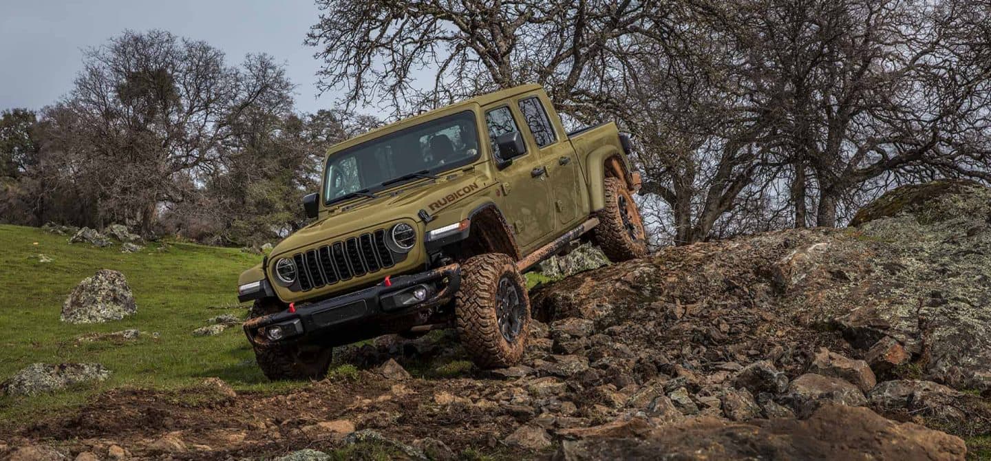 Una Jeep Gladiator Rubicon X 2025 verde oliva descendiendo por un sendero todoterreno rocoso e irregular.