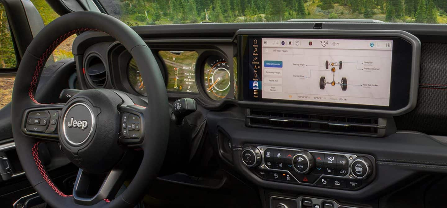 El volante, el panel de instrumentos, la pantalla táctil Uconnect y los controles de la consola central de Jeep Gladiator 2025 con la pantalla táctil en donde se observa la sección Dinámica del vehículo de las Páginas todoterreno.