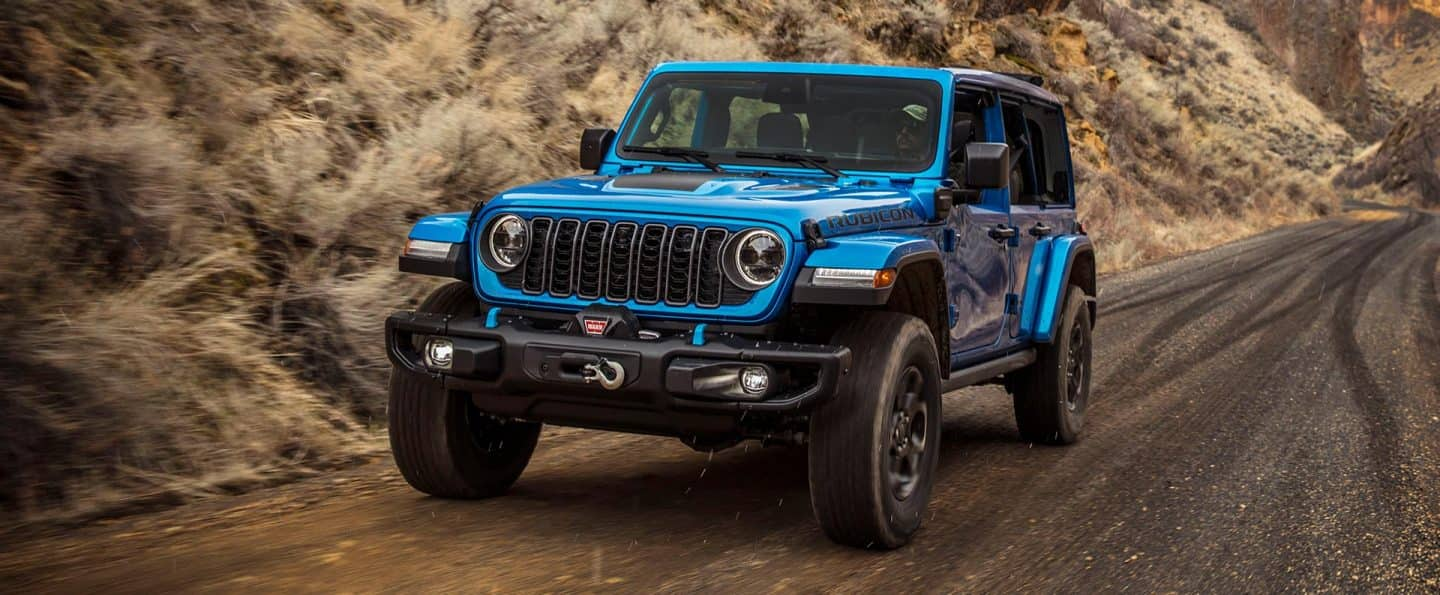 Un Jeep Wrangler X 4xe 2025 azul circulando por una carretera.