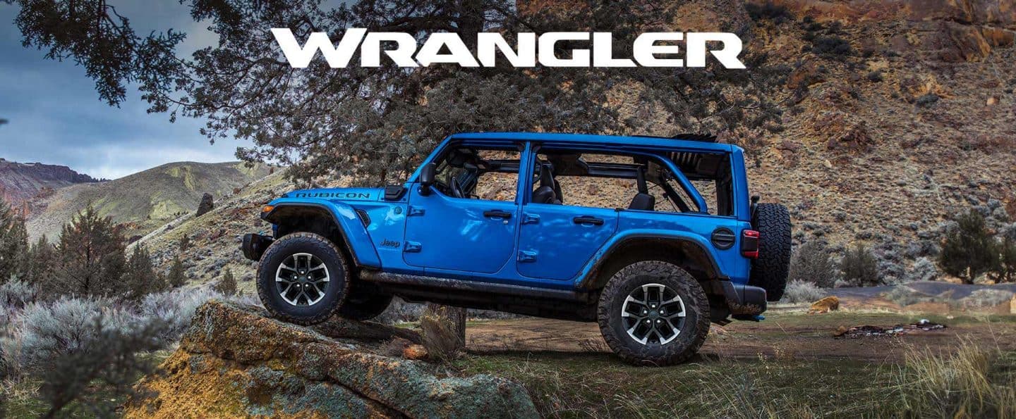 Perfil del lado del conductor de un Jeep Wrangler Rubicon X 4xe 2025 azul estacionado fuera de la carretera, con los neumáticos delanteros elevados en una formación rocosa. Wrangler.