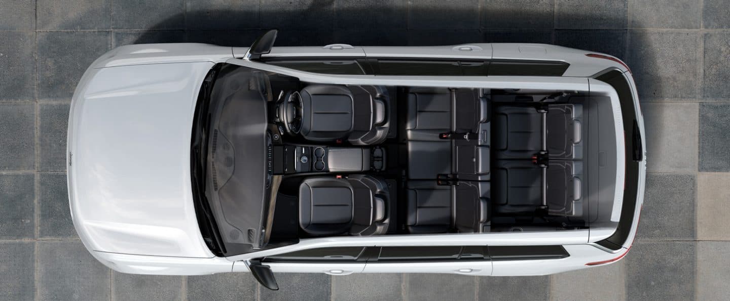 The cockpit of the 2023 Jeep Grand Cherokee Summit Reserve with a view of a lake at sunset through the windshield.