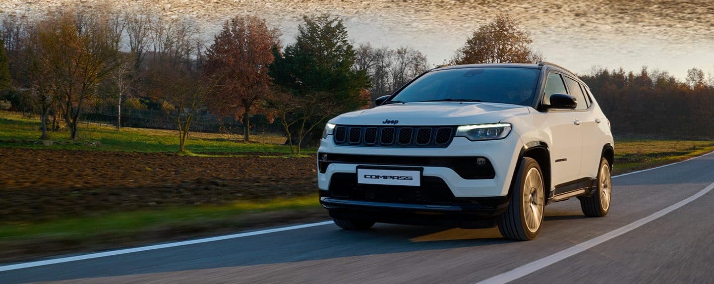 A white 2024 Jeep Grand Cherokee Trailhawk 4xe with a black hood insert, being driven off-road.