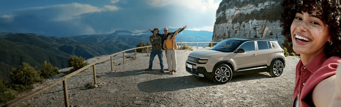 A white 2023 Jeep Wrangler Rubicon 4xe and a lime green 2023 Jeep Gladiator Rubicon, both with their doors and roofs removed, parked opposite of each other on sand at the foot of a large, rocky hill. Memorial Day Sales Event.