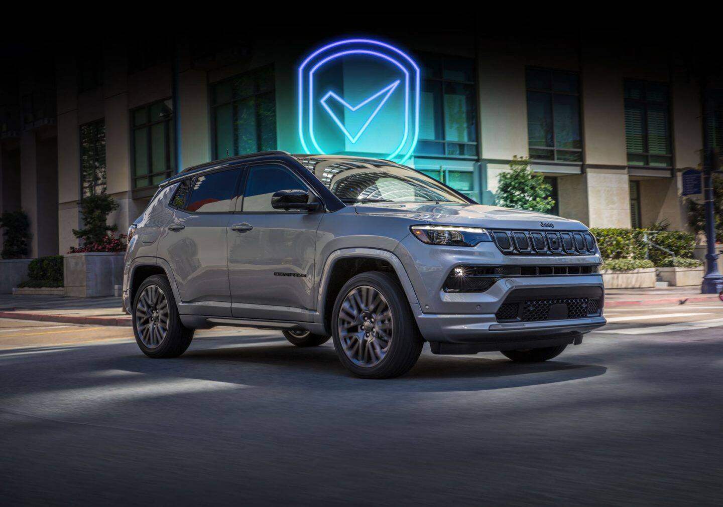 A rear view of a 2023 Jeep Compass High Altitude being driven on a winding highway during a rainstorm.