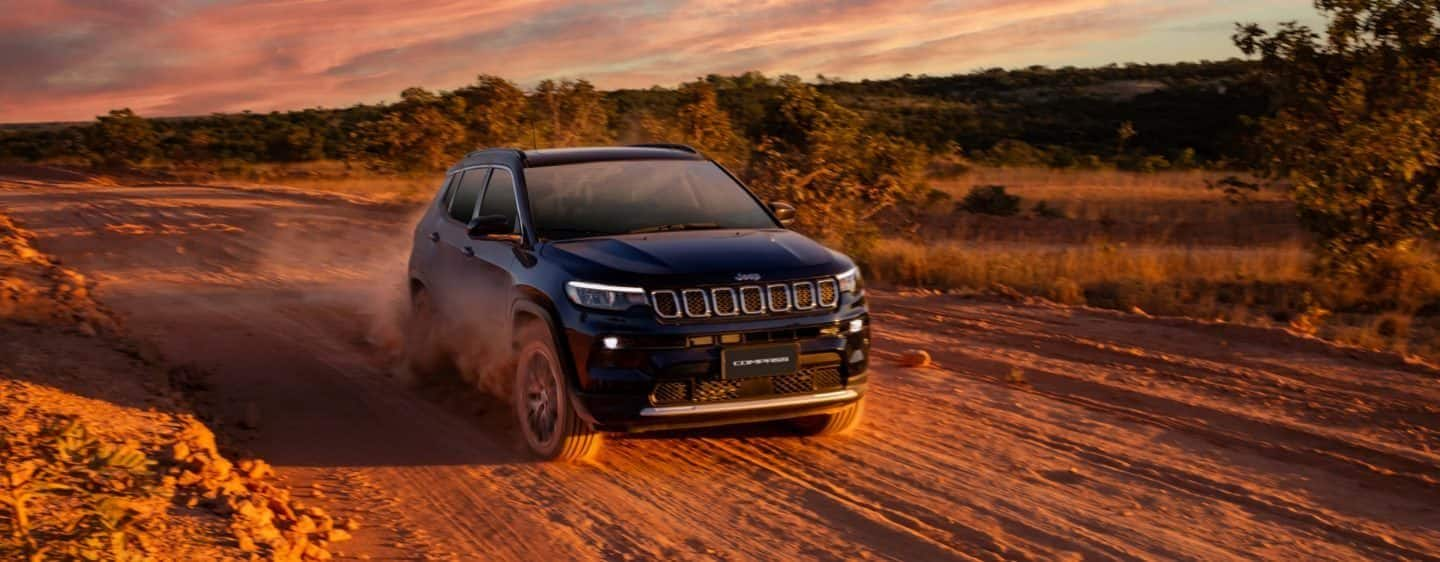 Un Jeep Compass 2023, siento conducido por terreno árido en pleno atardecer