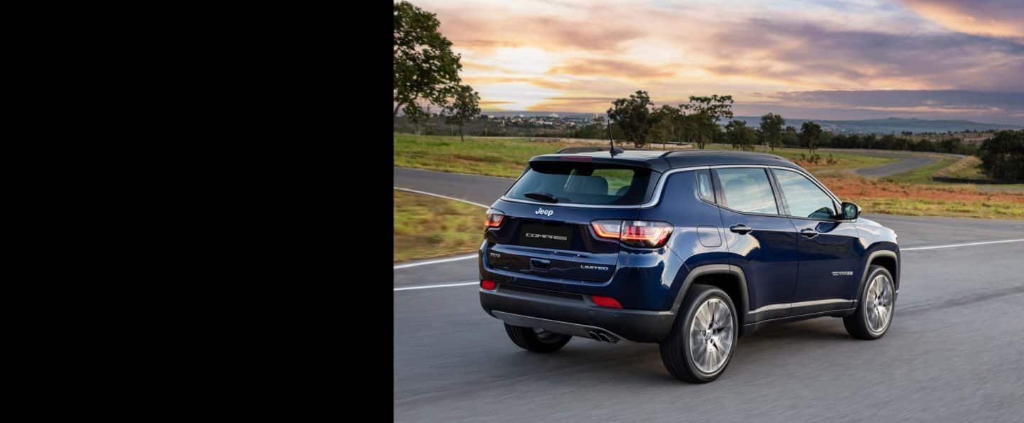 Un Jeep Compass 2023 siendo conducido sobre la carretera con un atardecer en el fondo.