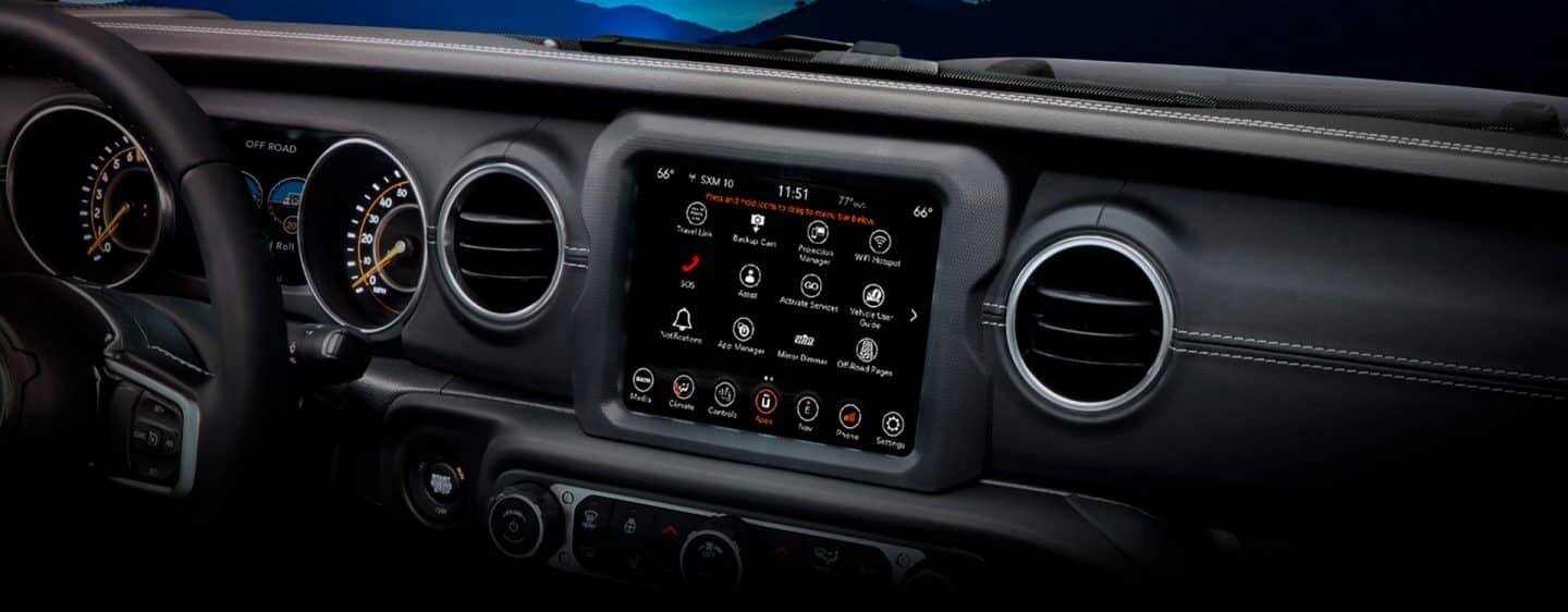 The dashboard in the 2023 Jeep Wrangler Rubicon, focusing on the steering wheel, touchscreen and climate controls.