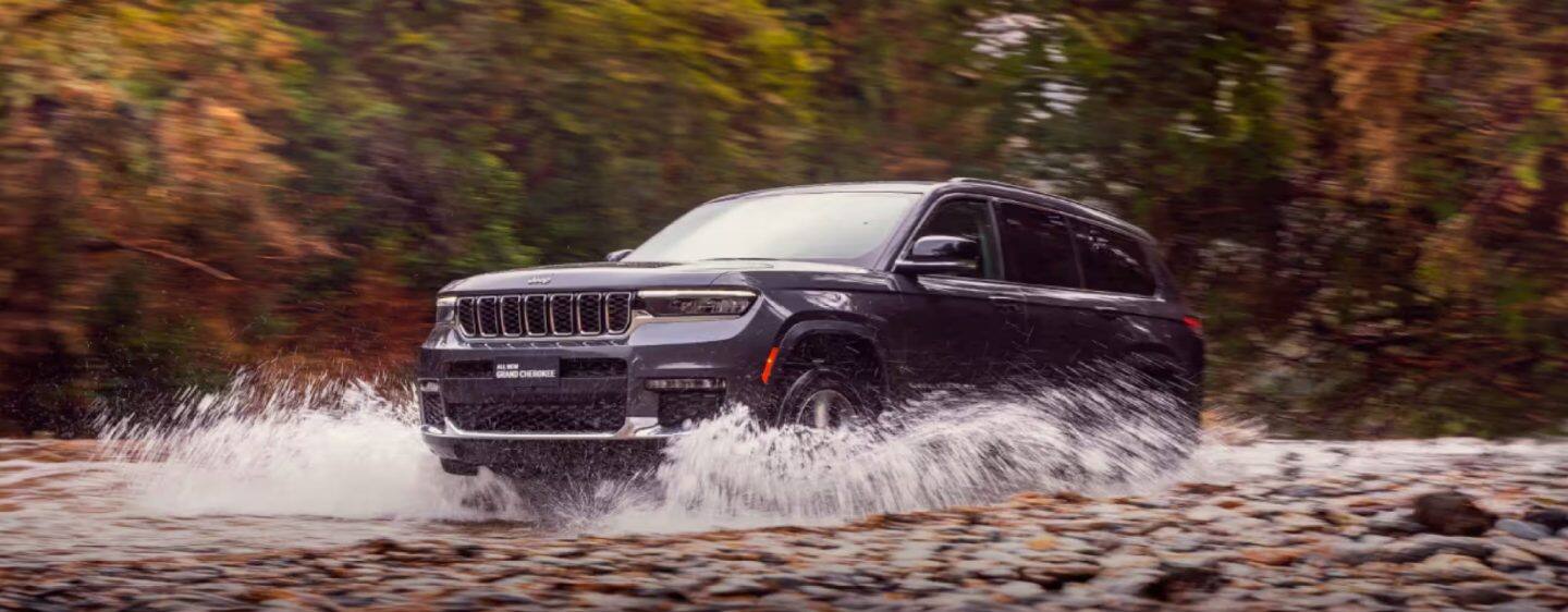 The 2023 Jeep Grand Cherokee 4xe climbing up a steep mountain trail with another Grand Cherokee 4xe following.