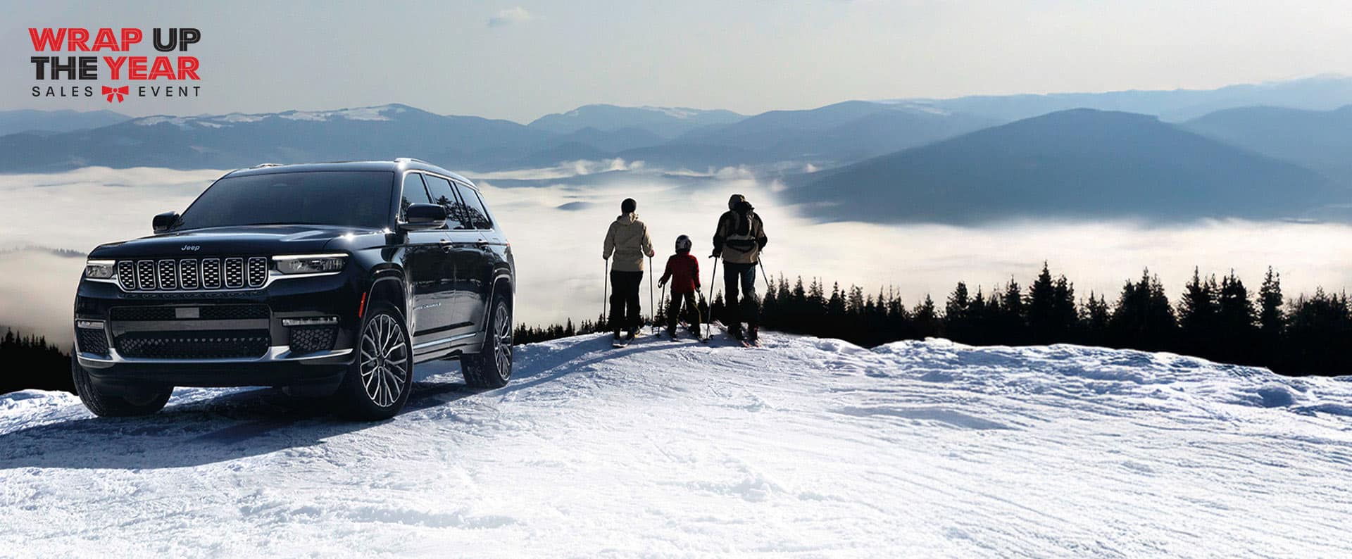 A black 2024 Jeep Grand Cherokee Summit Reserve parked on a snow-covered hill with a family of three in ski gear standing nearby and mountains in the background. Wrap Up the Year Sales Event. 