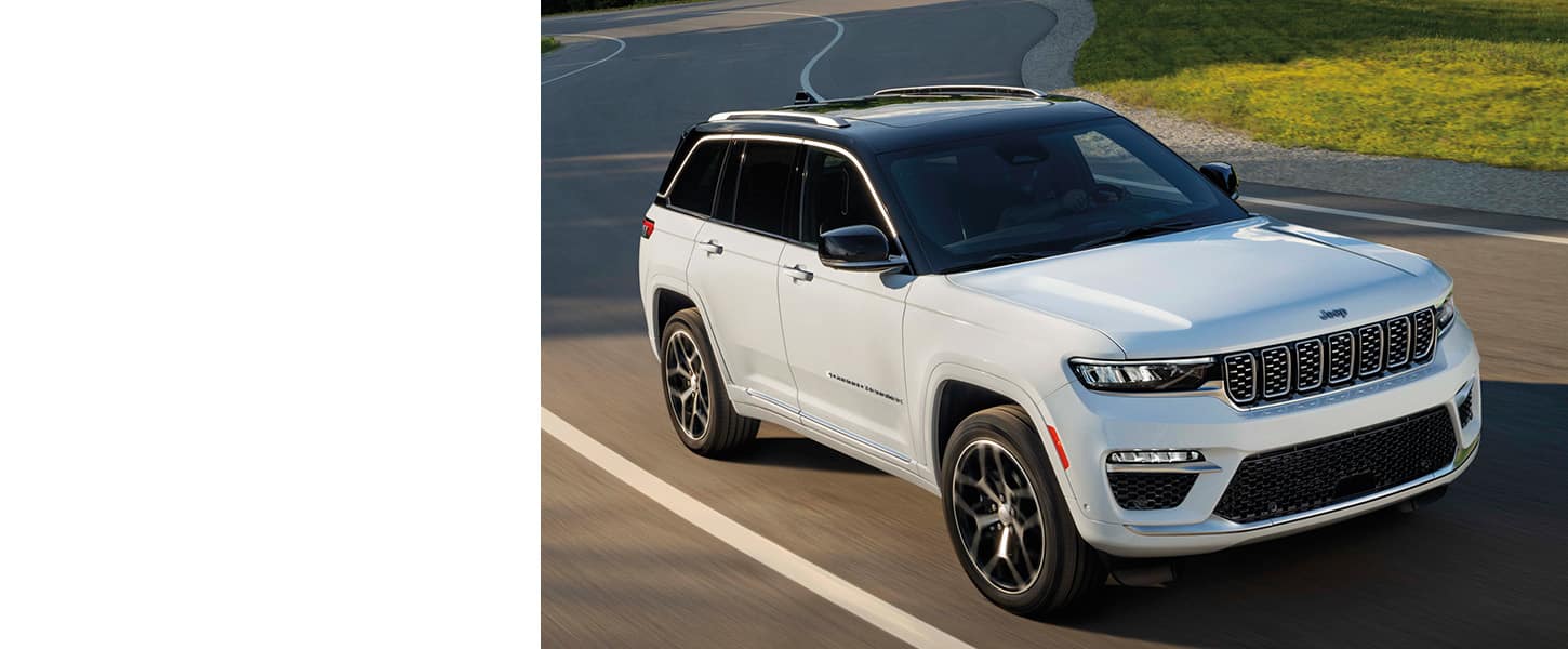 A white 2024 Jeep Grand Cherokee Summit Reserve being driven on a curved highway.