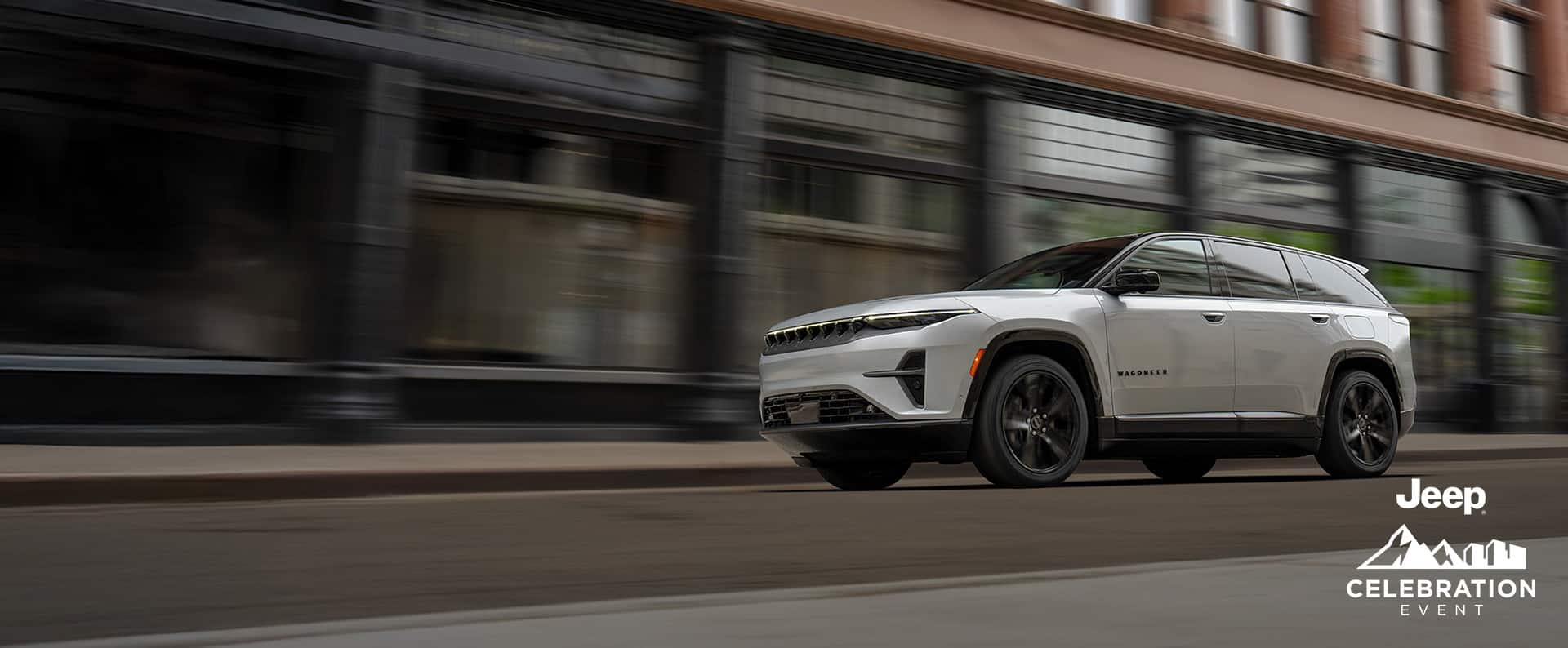 A silver 2024 Jeep Wagoneer S Launch Edition travelling on a city street with the background blurred. Jeep Celebration Event.