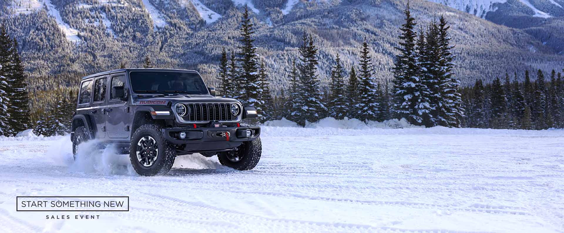 A gray 2024 Jeep Wrangler Rubicon traveling on a snow-covered trail in a forest. Start Something New Sales Event logo.