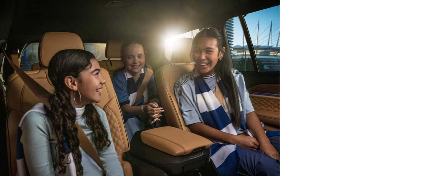 The interior of the 2025 Jeep Grand Cherokee L Summit with two children seated in the second row and one child seated in the third row.