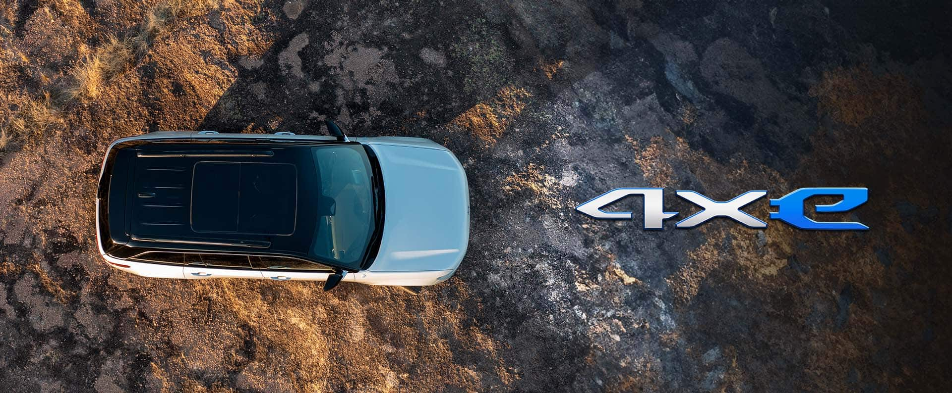 An overhead angle of a white 2025 Jeep Grand Cherokee Summit Reserve 4xe parked off-road. The 4xe badge.