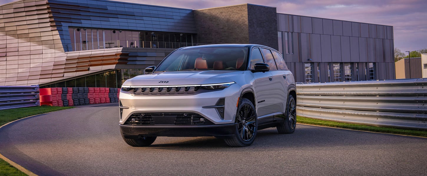 Un Jeep Wagoneer S Launch Edition 2025 plateado en la entrada circular de un edificio comercial.