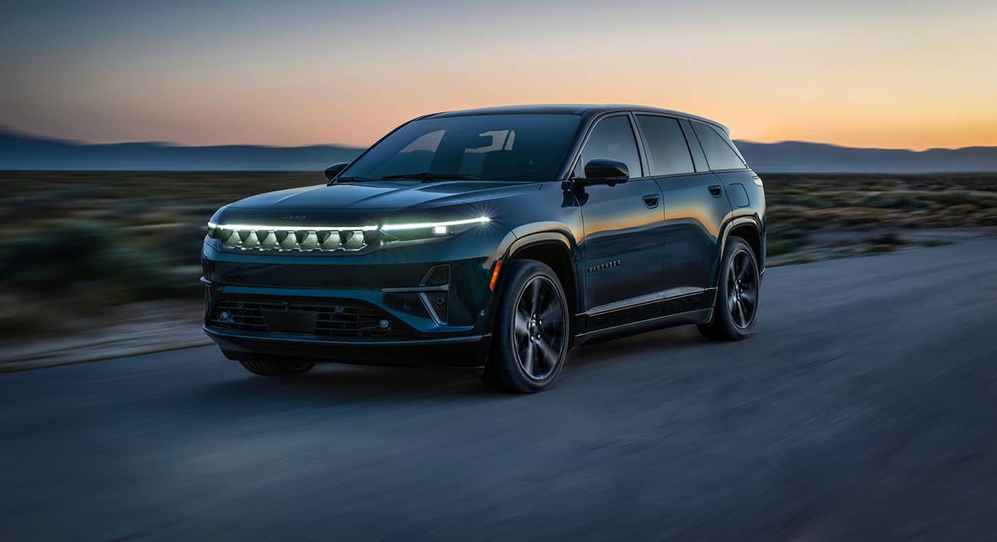 A black 2025 Jeep Wagoneer S Launch Edition traveling on a desert highway at dusk.