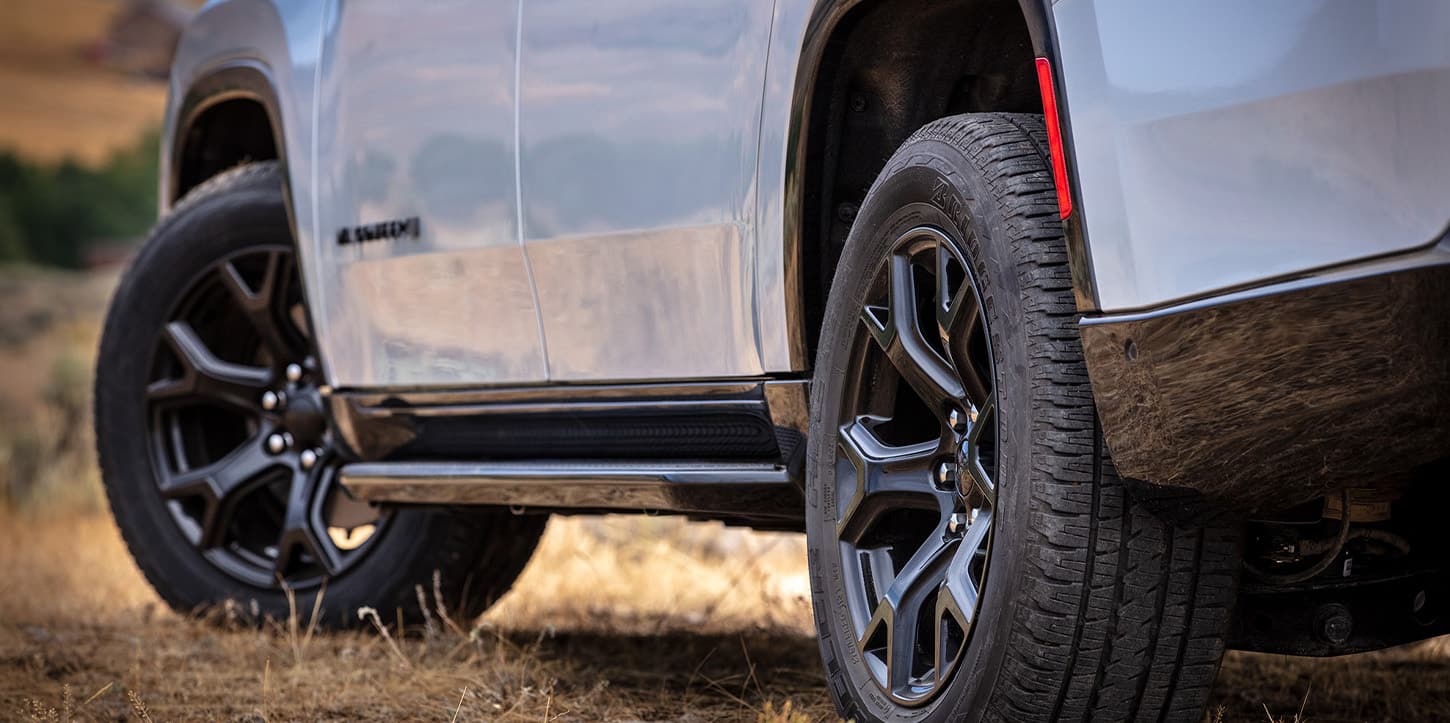 The driver-side front and rear wheels on a white 2025 Jeep Wagoneer Carbide.