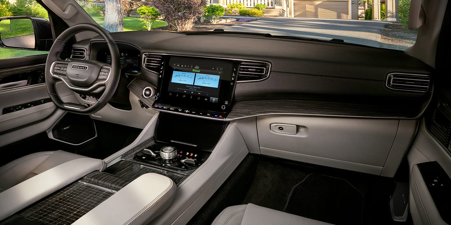 The front row of the 2025 Jeep Wagoneer Series III cabin, focusing on the seats, steering wheel, touchscreen, center console and controls and dash.