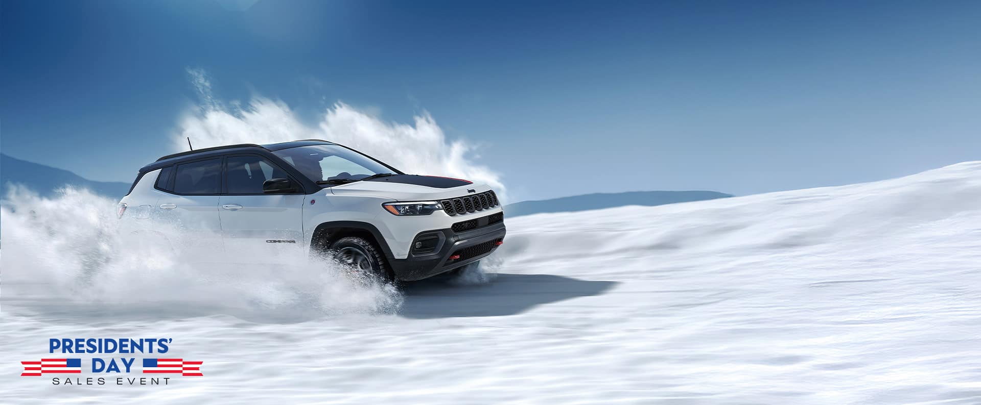 A white 2026 Jeep Compass Trailhawk with a black hood insert and black roof, traveling on a trail off-road, kicking up snow as it goes. The Presidents' Day Sales Event.