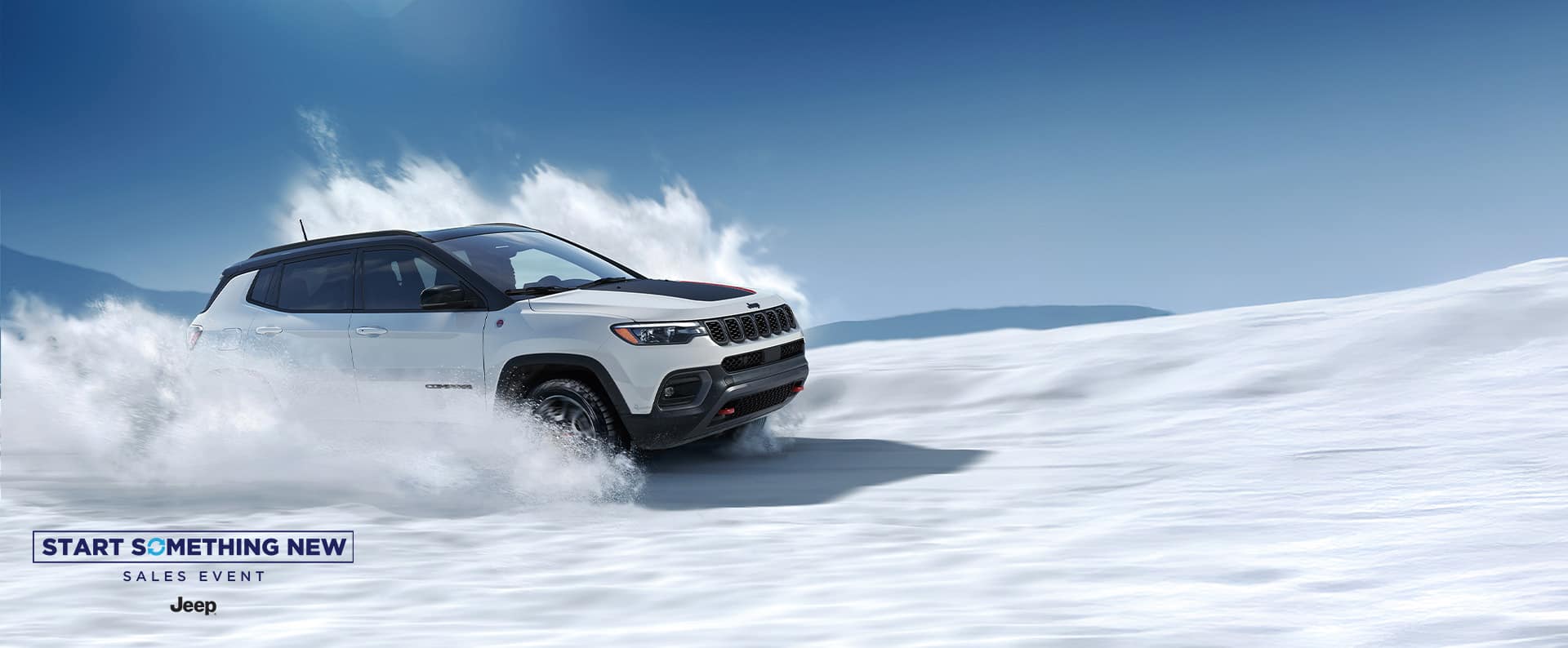 A white 2026 Jeep Compass Trailhawk with black hood insert, traveling through a snowy trail off-road. The Wrap Up The Year Sales Event.