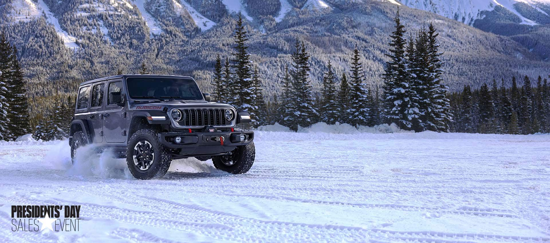 A gray 2024 Jeep Wrangler Rubicon traveling on a snow-covered trail in a forest. President's day event.