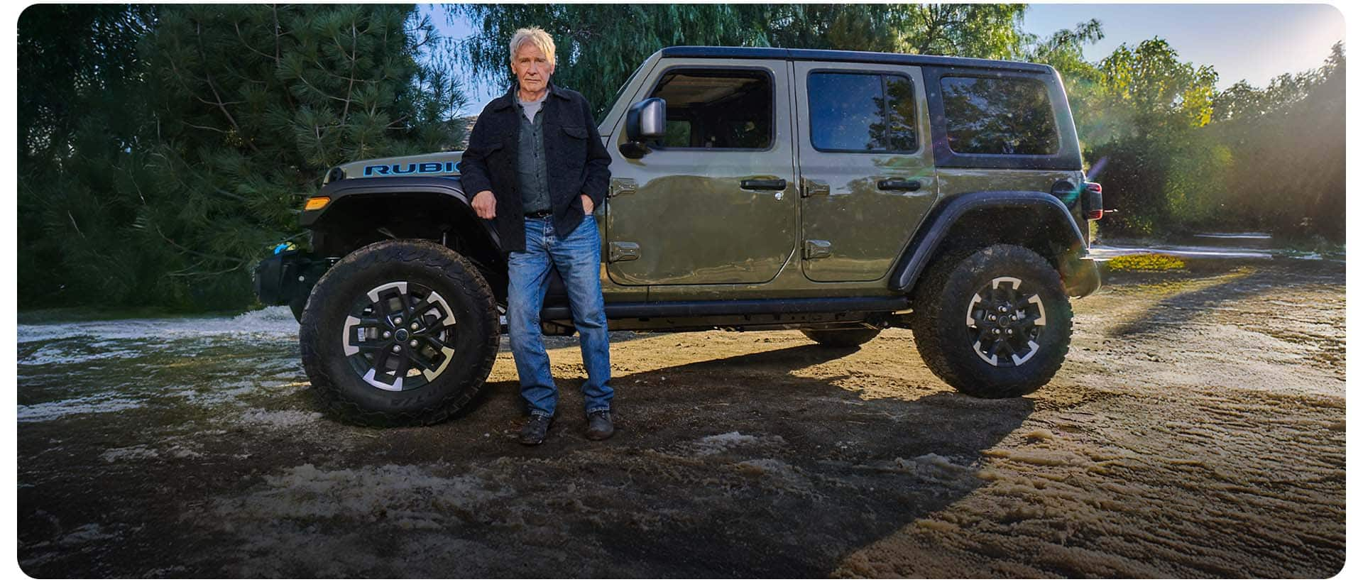 Harrison Ford standing beside an olive green 2025 Jeep Wrangler Rubicon 4xe.