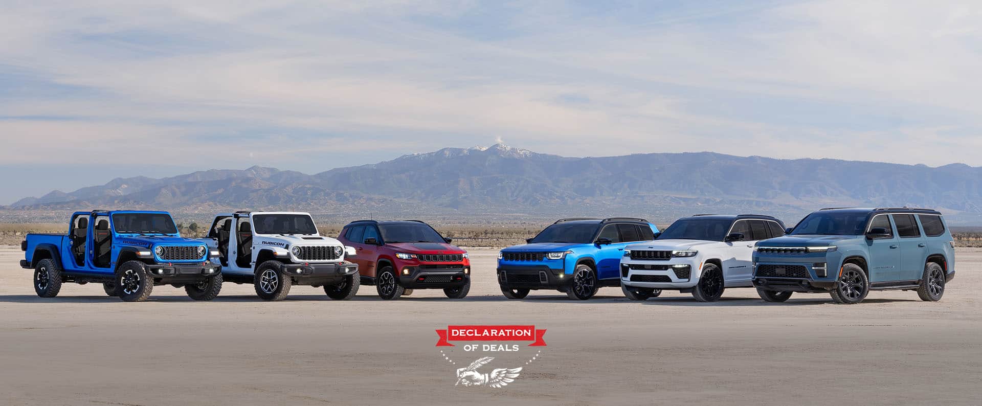 A lineup of six 2026 Jeep Brand vehicles parked in a semicircle. From left to right: a blue Gladiator Rubicon and white Wrangler Rubicon X—both with their doors and tops removed, a red Compass Trailhawk with black hood insert, a blue Cherokee Overland, a white Grand Cherokee Summit Obsidian, and a blue gray Grand Wagoneer Upland. Declaration of Deals.