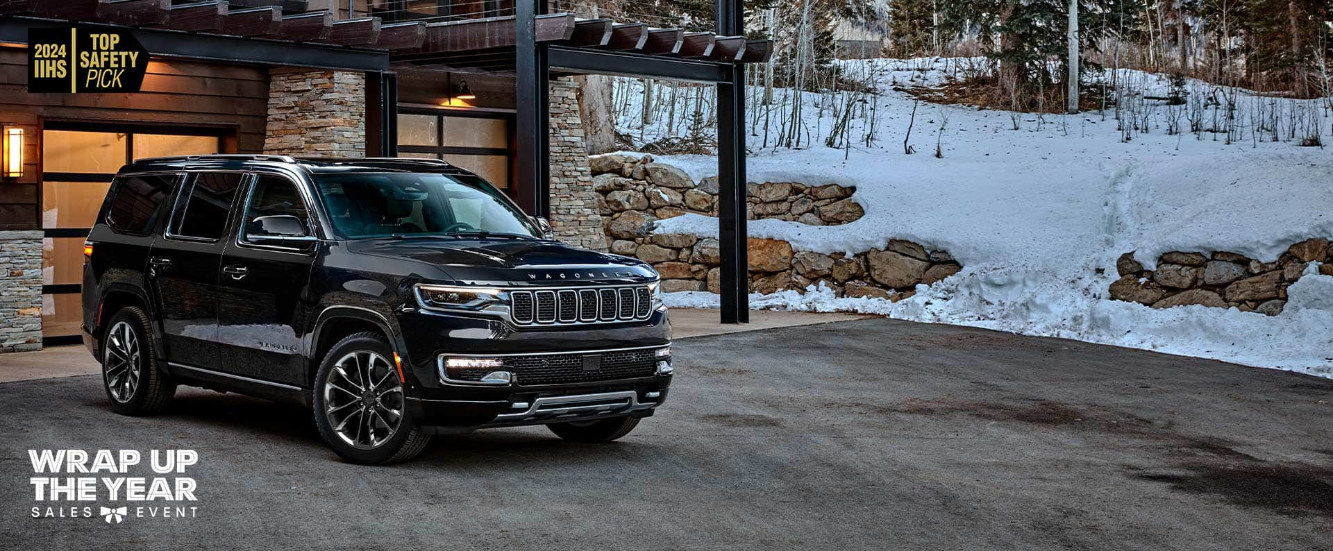 A black 2024 Jeep Wagoneer Series III parked in the driveway of a luxurious mountain chalet. Wrap Up The Year Sales Event logo. 