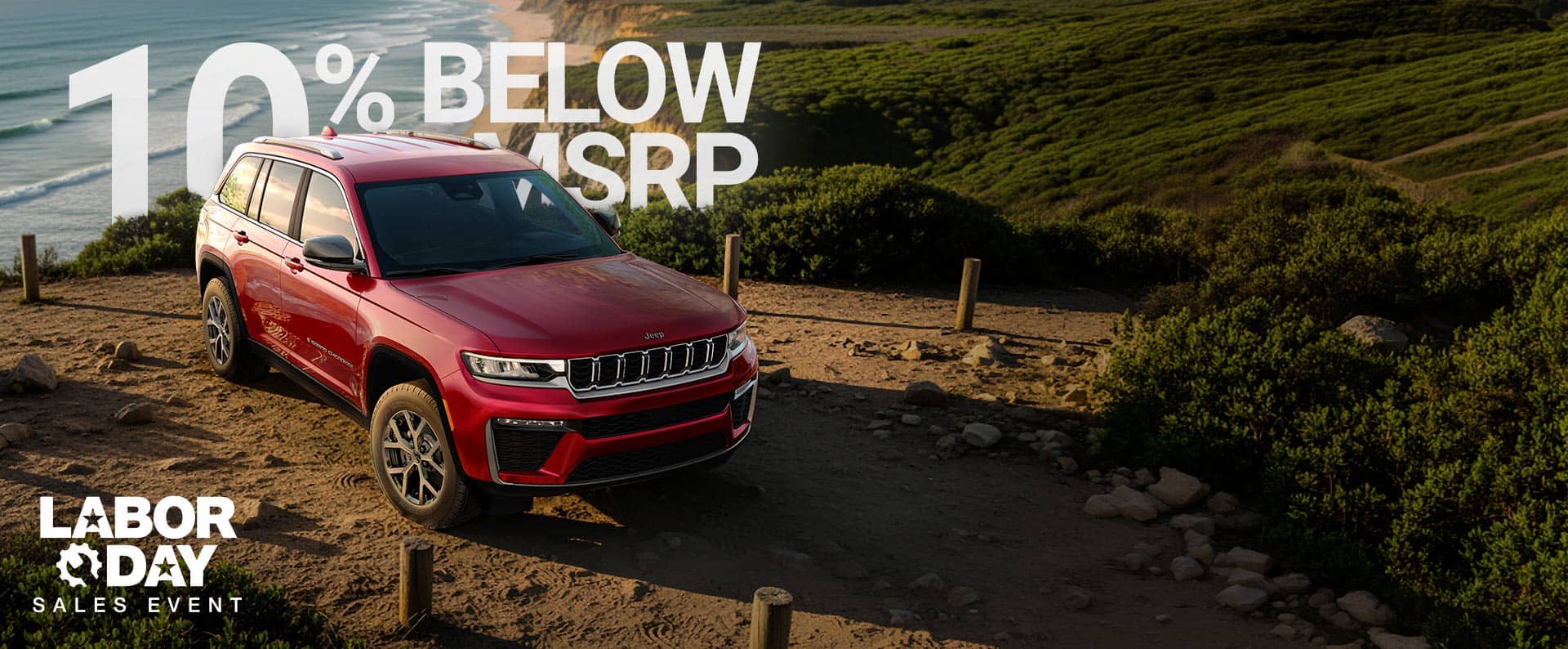 A red 2026 Jeep Grand Cherokee Limited parked on a beach near the shoreline. 520 + Miles. Labor Day Sales Event.