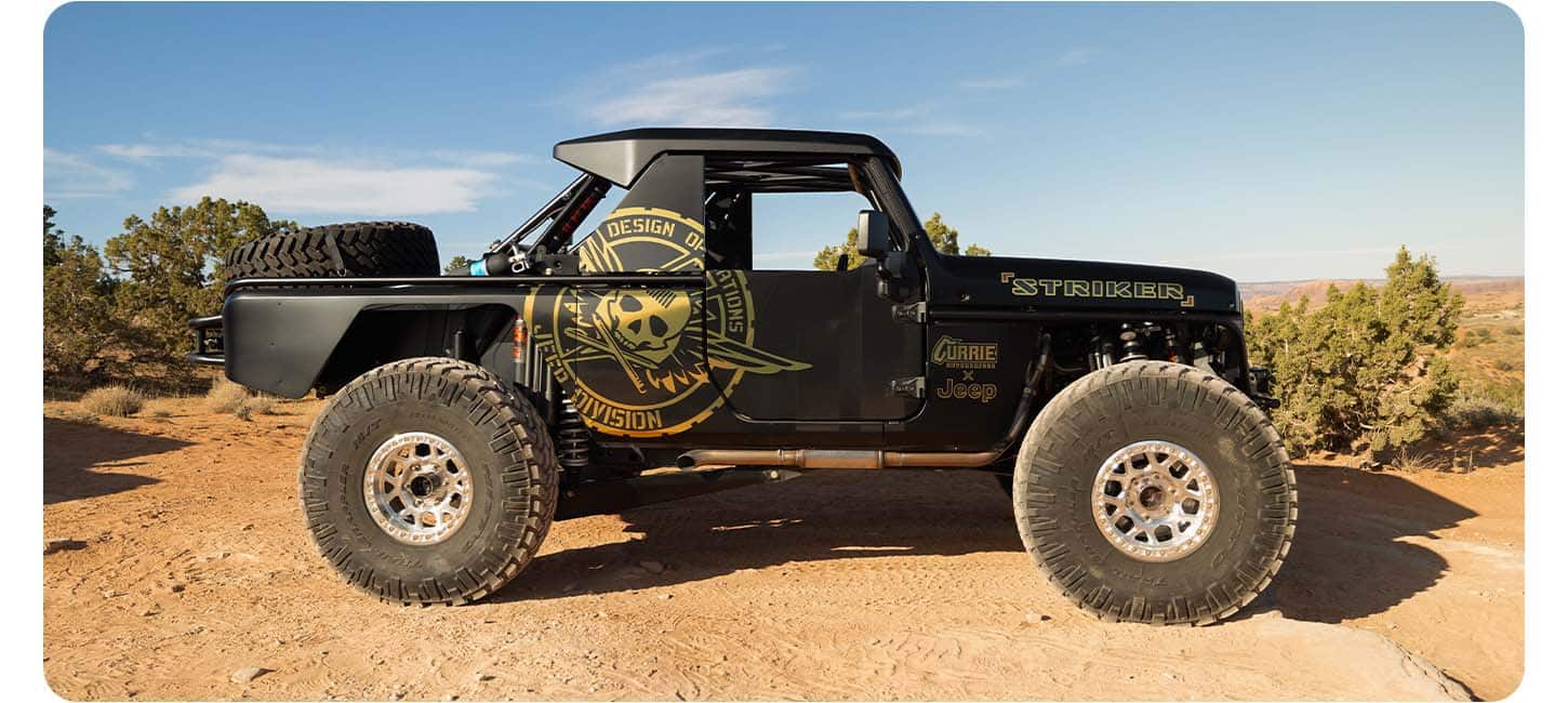 The black Jeep Wrangler Striker Concept Vehicle in profile, with oversize tires and several unique decals and badging.