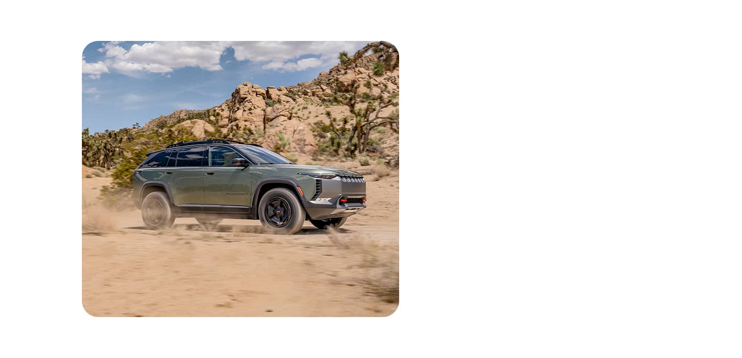 A passenger-side profile of a gray Wagoneer S Trailhawk Concept Vehicle kicking up dust as it travels off-road in the desert.