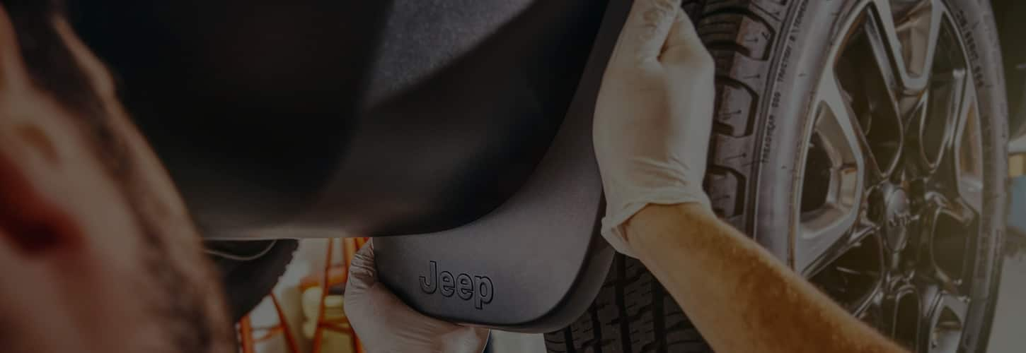 Close-up of hands working on a Jeep Brand vehicle.